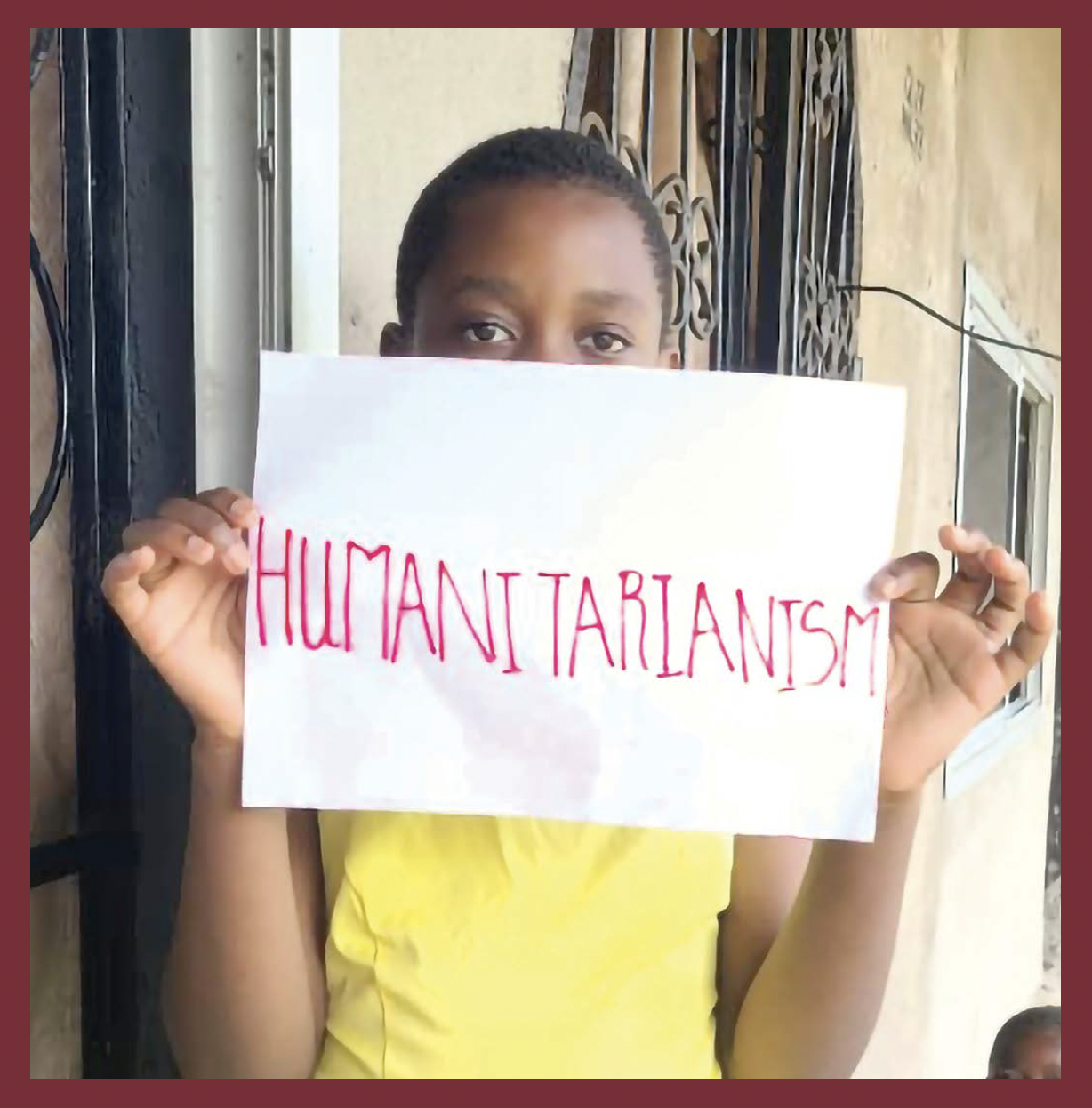 A young person holding a sign that reads humanitarianism