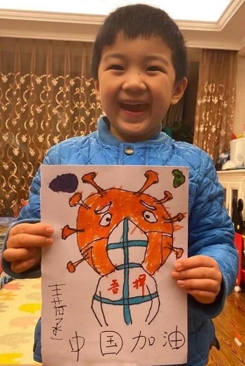 A child is beaming with happiness holding their drawing.