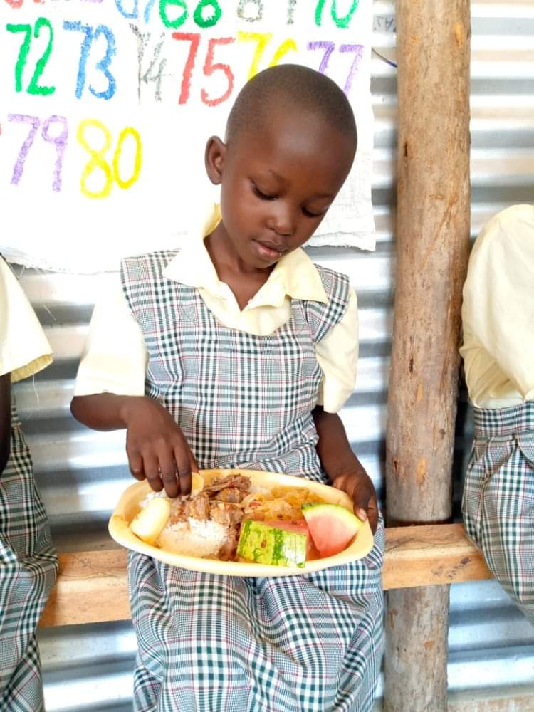 Kenyan student sitting with a plate of food.