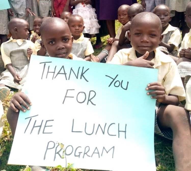 Students giving a thumbs up and showing a sign reading Thank you for the Lunch Program.