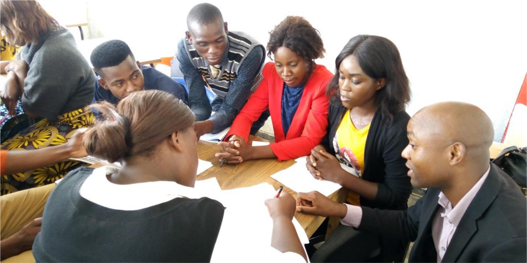 Teachers consult together at a table working through plans.