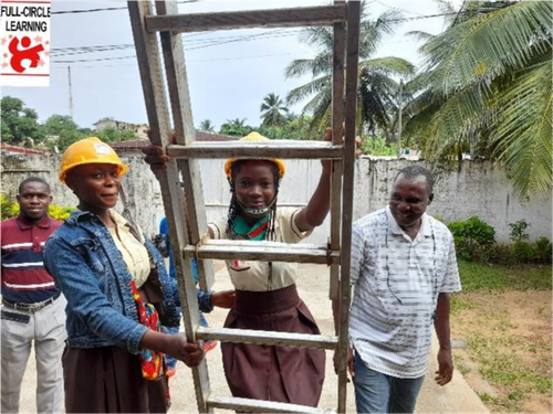 A student begins to climb a ladder assisted by her Teacher.