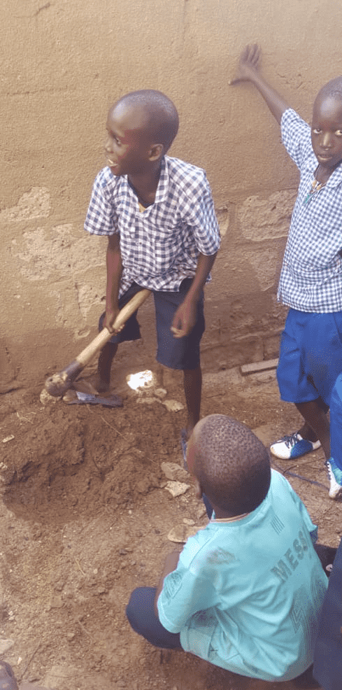 A young student digs at the earth while others look on